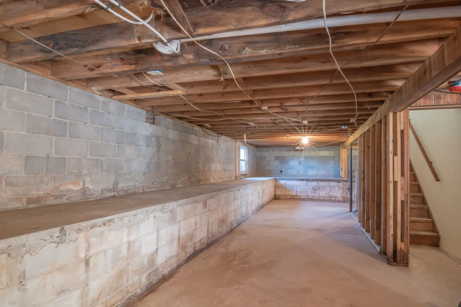 Unfinished basement crawl space with concrete block foundation walls and wood floor joists in Tulsa, Oklahoma